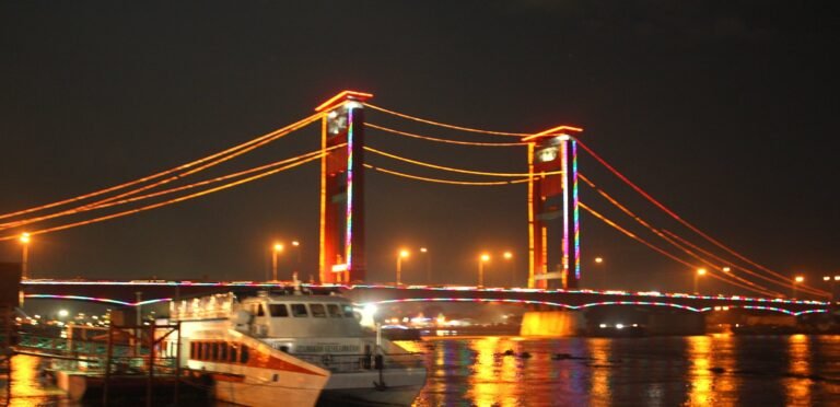Jembatan Ampera di malam hari dengan pantulan cahaya di Sungai Musi