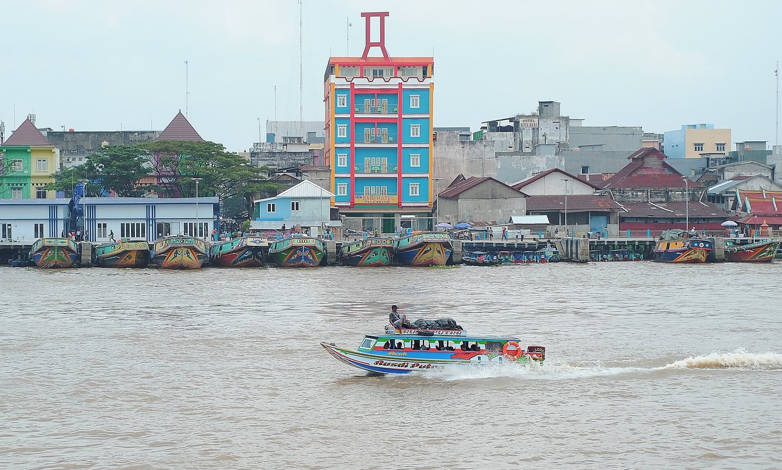 Perahu wisata menyusuri Sungai Musi dengan bangunan tepian